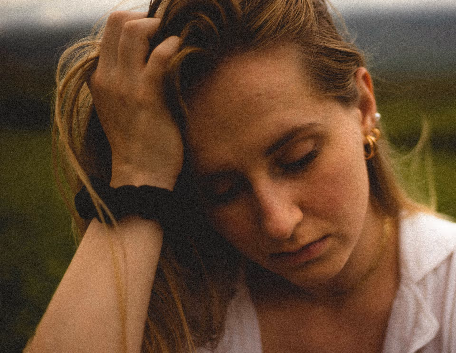 visage jeune femme déprimée, sa main droite retient la tête inclinée sur le côté et le regard vers le bas, intériorisé.