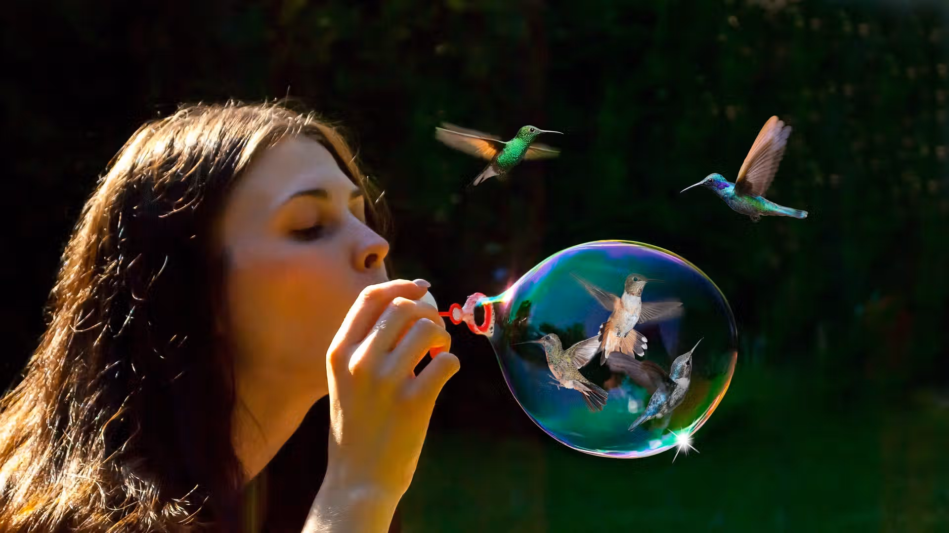 Une jeune fille souffle une grosse bulle de savon. Deux colibris volètent au dessus.